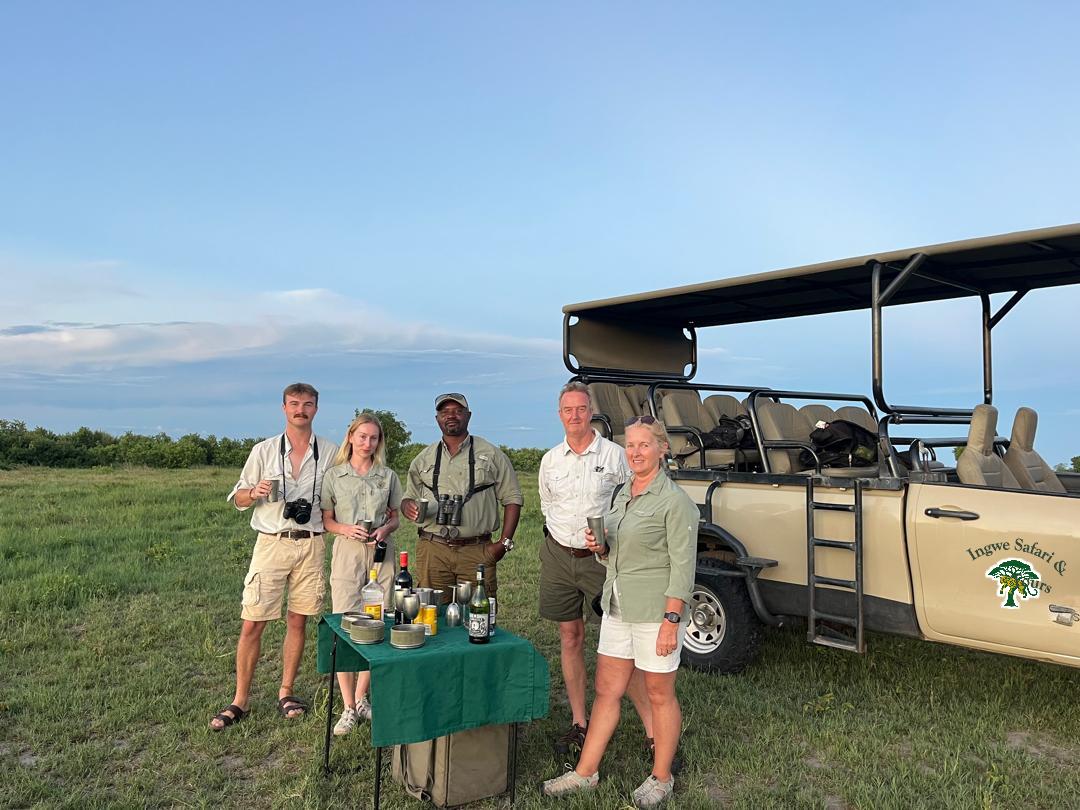 Ingwe Expert Safari & Tours guides and guests with sundowners beside the safari vehicle